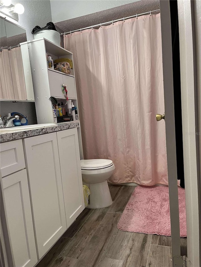 bathroom with hardwood / wood-style floors, vanity, and toilet