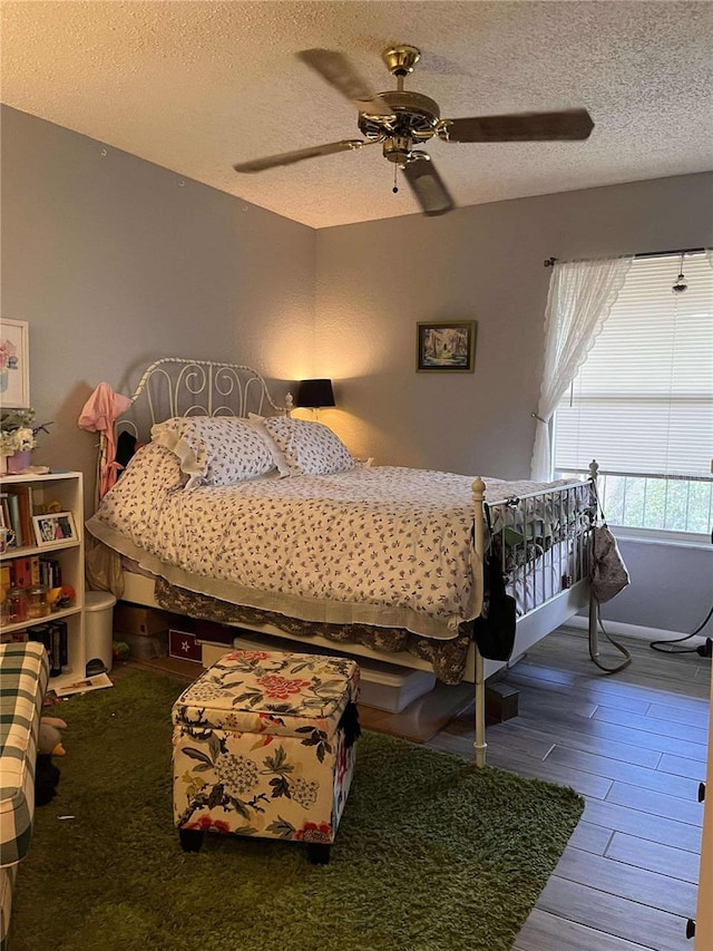 bedroom with a textured ceiling, dark hardwood / wood-style floors, and ceiling fan