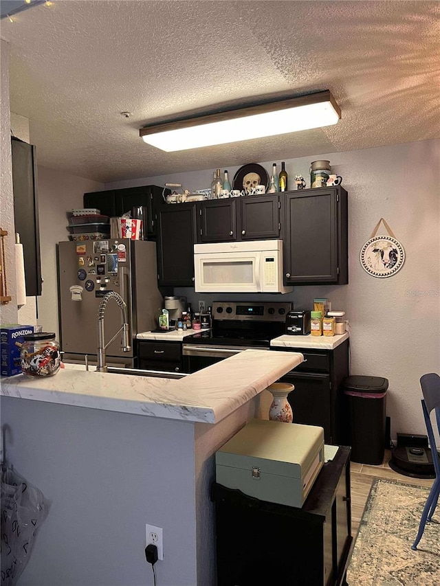 kitchen with kitchen peninsula, a textured ceiling, and appliances with stainless steel finishes