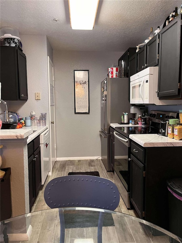 kitchen with a textured ceiling, light wood-type flooring, and stainless steel appliances