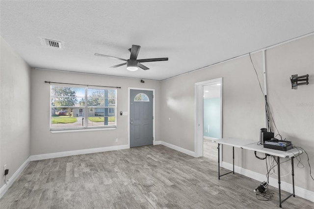 foyer entrance with a textured ceiling, light hardwood / wood-style flooring, and ceiling fan