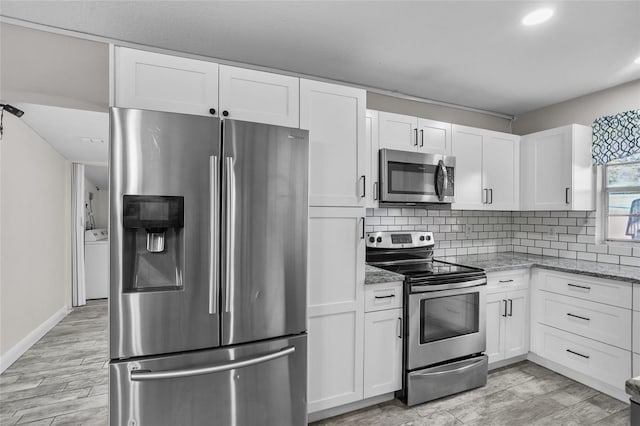 kitchen featuring tasteful backsplash, light stone counters, stainless steel appliances, washer / dryer, and white cabinetry