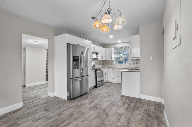 kitchen with sink, a chandelier, pendant lighting, white cabinets, and appliances with stainless steel finishes