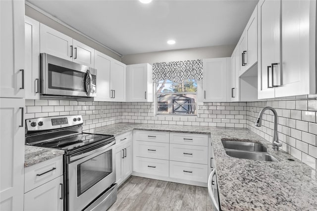 kitchen featuring appliances with stainless steel finishes, tasteful backsplash, white cabinetry, and sink