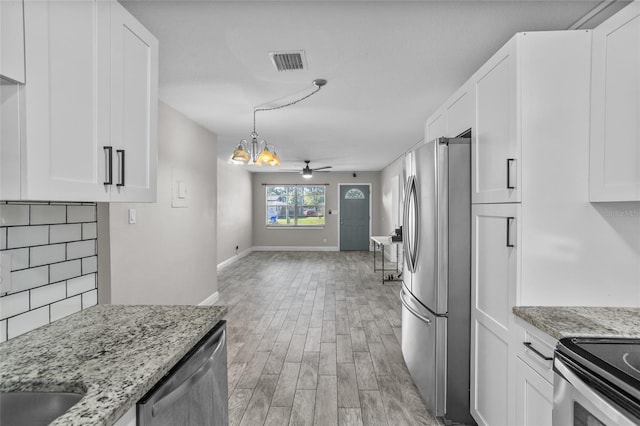 kitchen with white cabinets, ceiling fan with notable chandelier, light stone counters, and stainless steel appliances