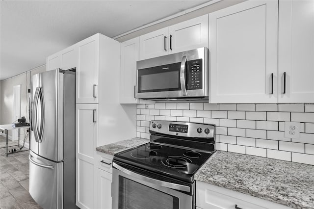 kitchen with white cabinets, decorative backsplash, light stone countertops, and appliances with stainless steel finishes