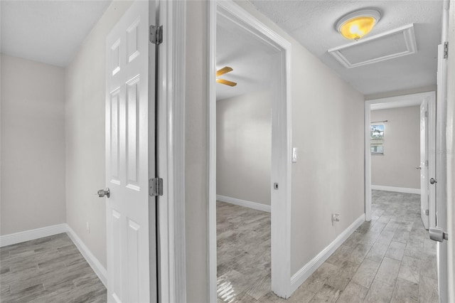 hall featuring a textured ceiling and light wood-type flooring