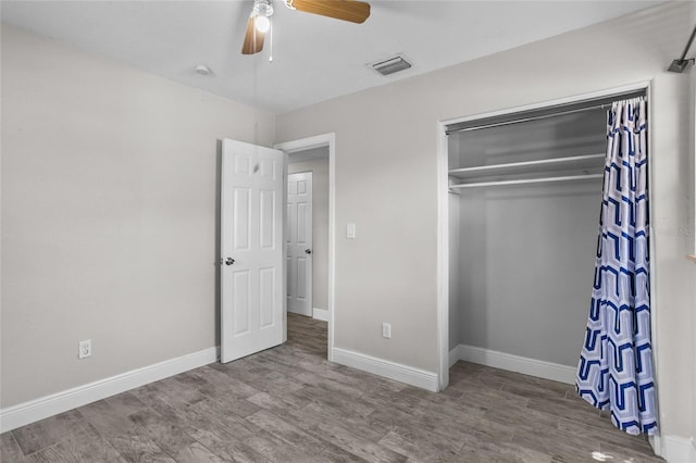 unfurnished bedroom featuring wood-type flooring, a closet, and ceiling fan