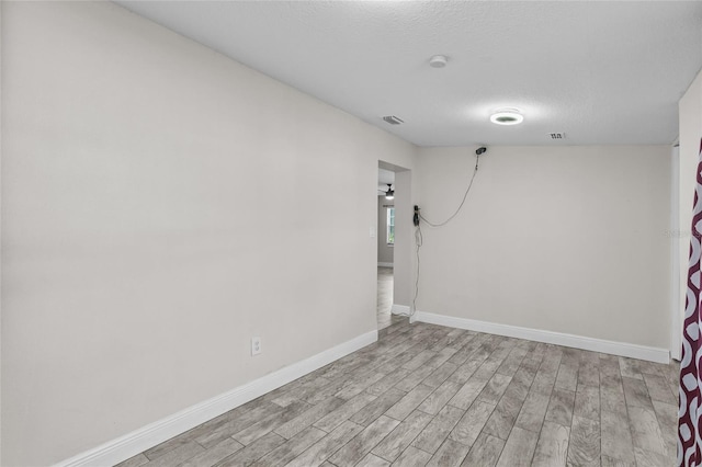 empty room with a textured ceiling and light hardwood / wood-style flooring