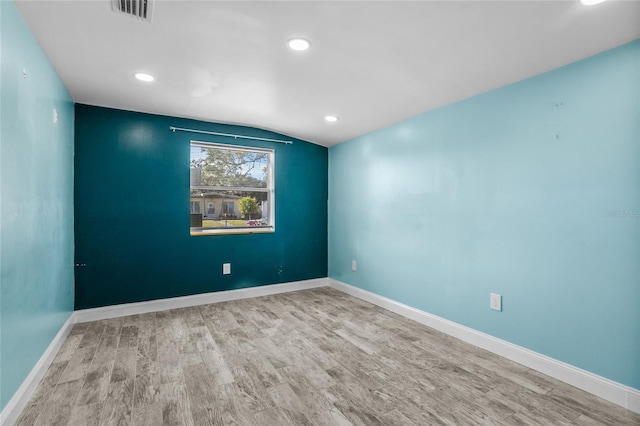 empty room with light hardwood / wood-style floors and lofted ceiling