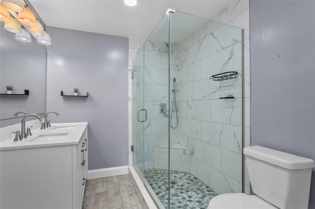 bathroom with a shower with door, vanity, hardwood / wood-style floors, and toilet