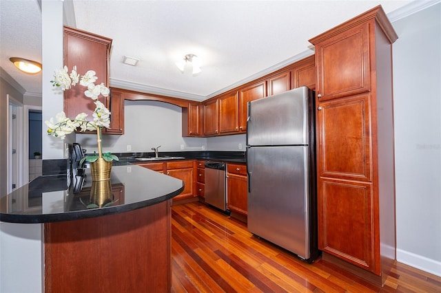 kitchen featuring sink, dark wood-type flooring, kitchen peninsula, appliances with stainless steel finishes, and ornamental molding