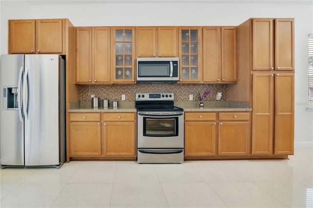 kitchen with light tile patterned floors, backsplash, and stainless steel appliances