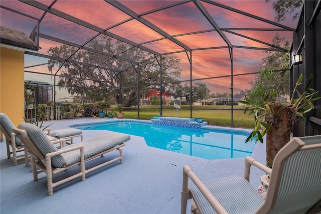 pool at dusk featuring glass enclosure, a patio area, and a yard