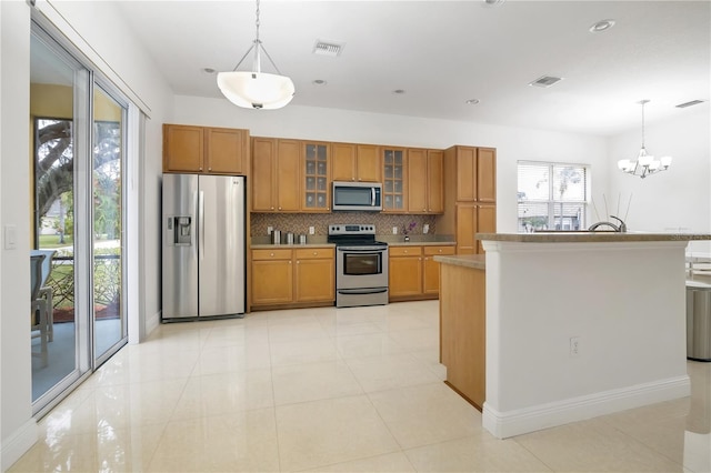 kitchen featuring appliances with stainless steel finishes, tasteful backsplash, light tile patterned floors, pendant lighting, and an inviting chandelier