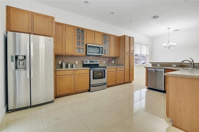 kitchen with backsplash, stainless steel appliances, sink, pendant lighting, and a notable chandelier