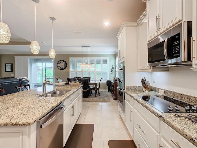 kitchen with white cabinetry, sink, stainless steel appliances, decorative light fixtures, and a kitchen island with sink