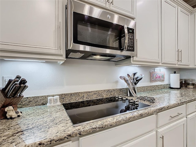 kitchen with white cabinets, light stone counters, and black electric cooktop