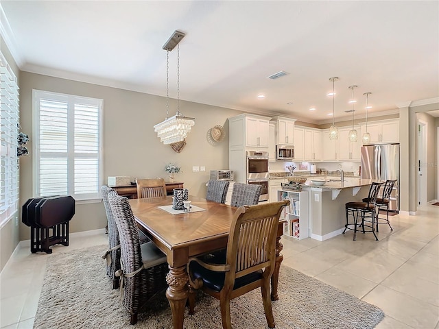 dining area featuring sink, light tile patterned floors, ornamental molding, and an inviting chandelier