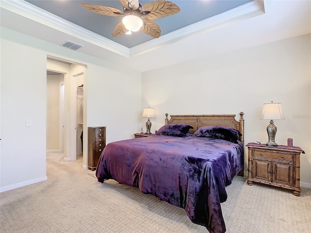 bedroom with ceiling fan, ornamental molding, light carpet, and a tray ceiling