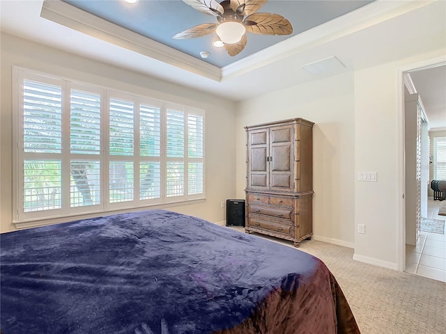 carpeted bedroom with ceiling fan, a raised ceiling, and crown molding