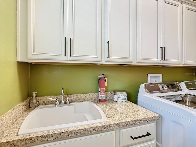 laundry area with cabinets, washer and clothes dryer, and sink