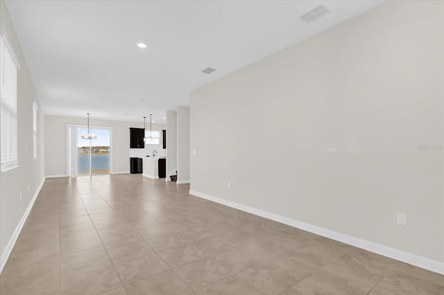 unfurnished living room with a chandelier and light tile patterned floors