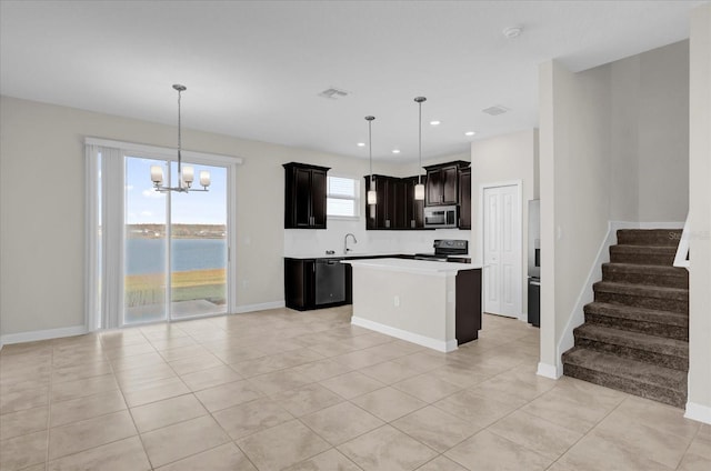 kitchen with a notable chandelier, pendant lighting, a water view, a kitchen island, and appliances with stainless steel finishes