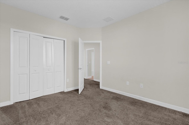 unfurnished bedroom with dark carpet and a closet