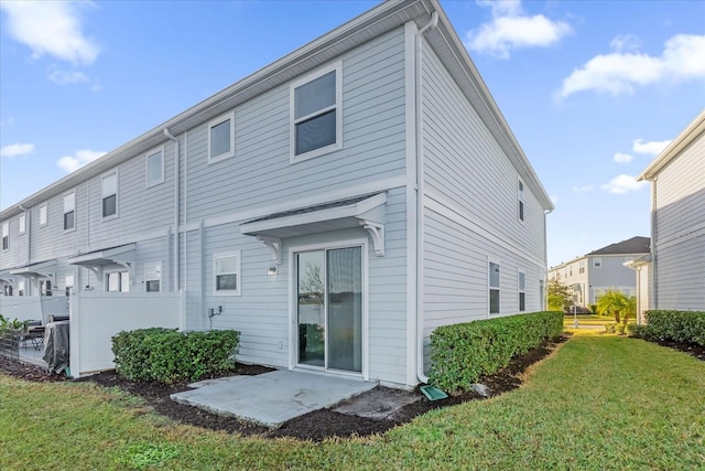 back of house with a patio and a lawn