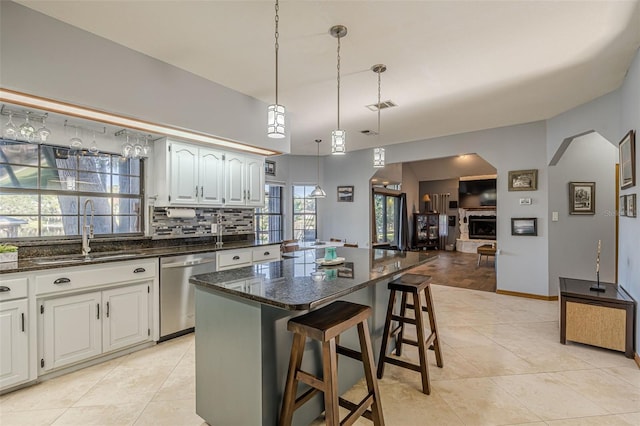 kitchen with white cabinets, dishwasher, a center island, a kitchen bar, and sink