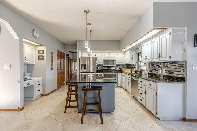 kitchen featuring white cabinets, a kitchen island, stainless steel appliances, backsplash, and a breakfast bar area