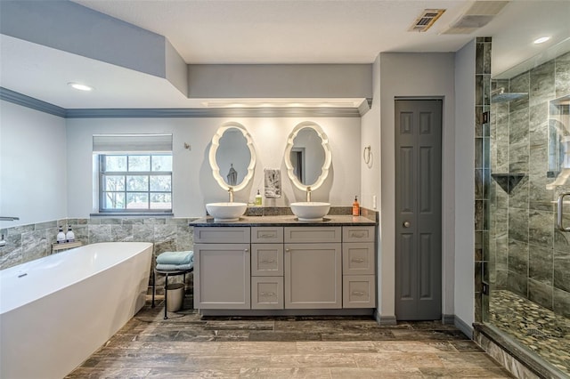 bathroom with wood-type flooring, vanity, tile walls, crown molding, and separate shower and tub