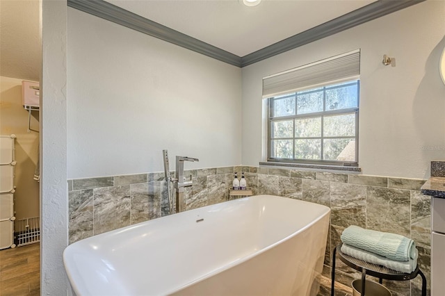 bathroom featuring a tub to relax in, tile walls, wood-type flooring, crown molding, and vanity