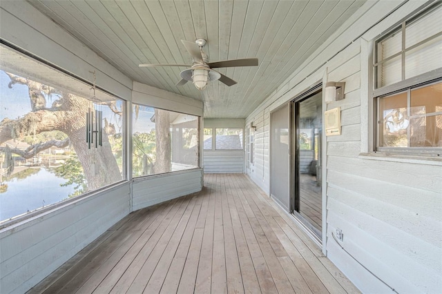 unfurnished sunroom with ceiling fan, wood ceiling, and a water view