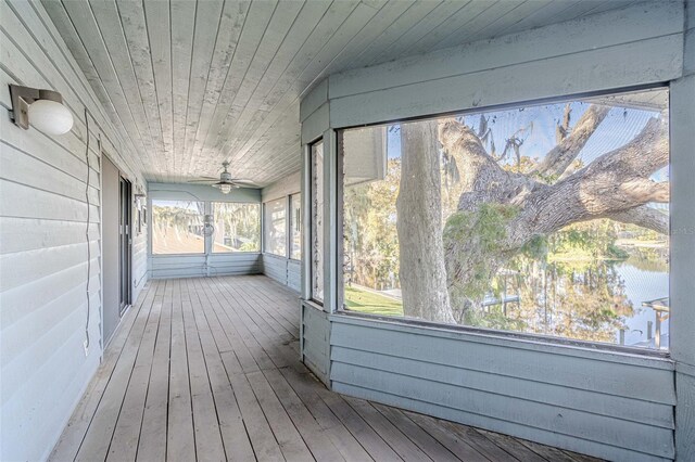 unfurnished sunroom with wooden ceiling, a water view, and ceiling fan