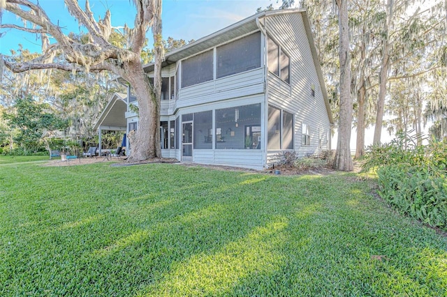 back of property featuring a sunroom and a lawn