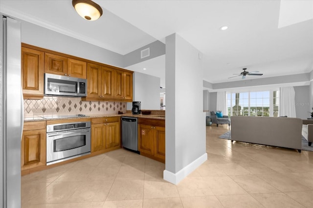 kitchen with tasteful backsplash, ceiling fan, light tile patterned floors, and stainless steel appliances