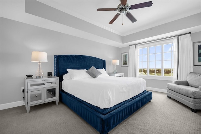 carpeted bedroom with ceiling fan and a tray ceiling