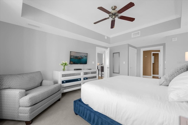 carpeted bedroom with ceiling fan and a raised ceiling