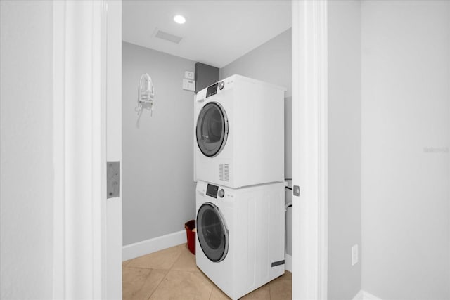 laundry room with stacked washing maching and dryer and light tile patterned flooring