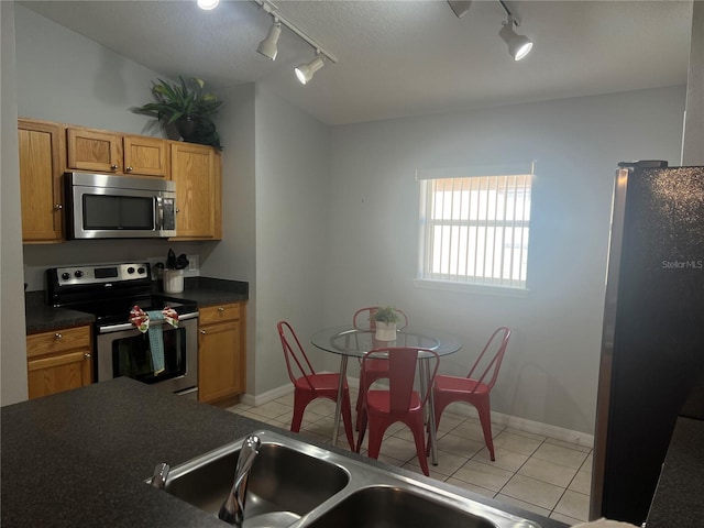 kitchen with light tile patterned flooring, sink, stainless steel appliances, and track lighting