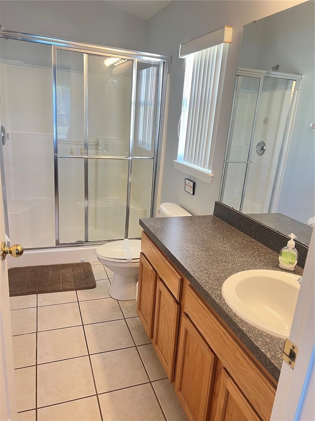 bathroom featuring tile patterned floors, a shower with door, vanity, and toilet