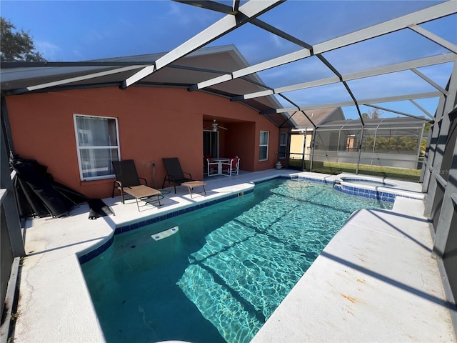 view of pool with glass enclosure, ceiling fan, a patio area, and an in ground hot tub