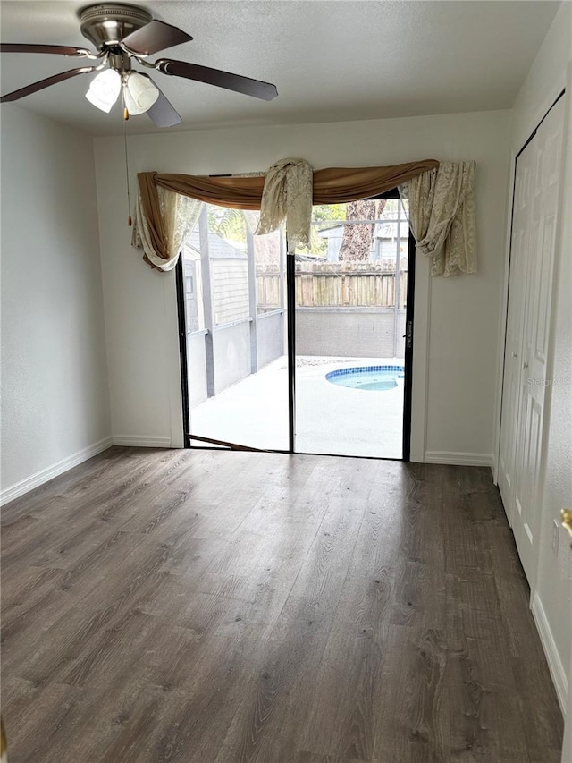 spare room with ceiling fan, a healthy amount of sunlight, and dark wood-type flooring