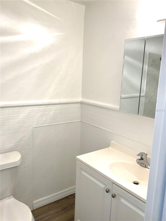 bathroom with hardwood / wood-style flooring, vanity, and toilet