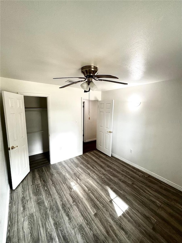 unfurnished bedroom with a textured ceiling, ceiling fan, a closet, and dark hardwood / wood-style floors