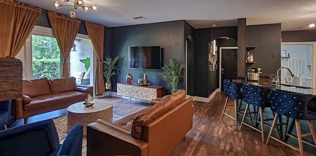 living room featuring a notable chandelier, dark hardwood / wood-style flooring, and a textured ceiling