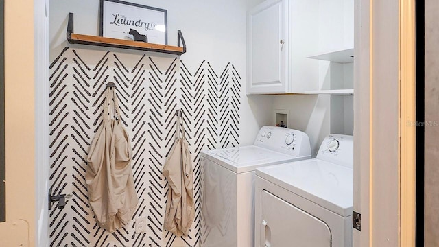 clothes washing area featuring washer and dryer and cabinets