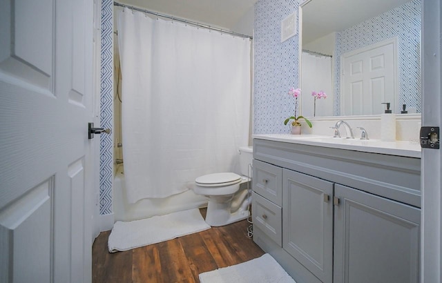 full bathroom with hardwood / wood-style floors, vanity, shower / tub combo, and toilet